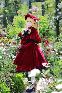 Rating: Safe Score: 0 Tags: 1girl blonde_hair blue_eyes blurry blurry_foreground bonnet bow capelet day depth_of_field dress flower garden looking_at_viewer looking_back outdoors photo red_dress shinku solo User: admin