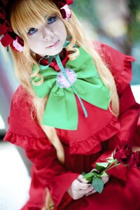 Rating: Safe Score: 0 Tags: 1girl blonde_hair blue_eyes blurry blurry_background bow capelet depth_of_field dress flower green_bow lips long_hair looking_at_viewer red_capelet ribbon rose shinku solo User: admin