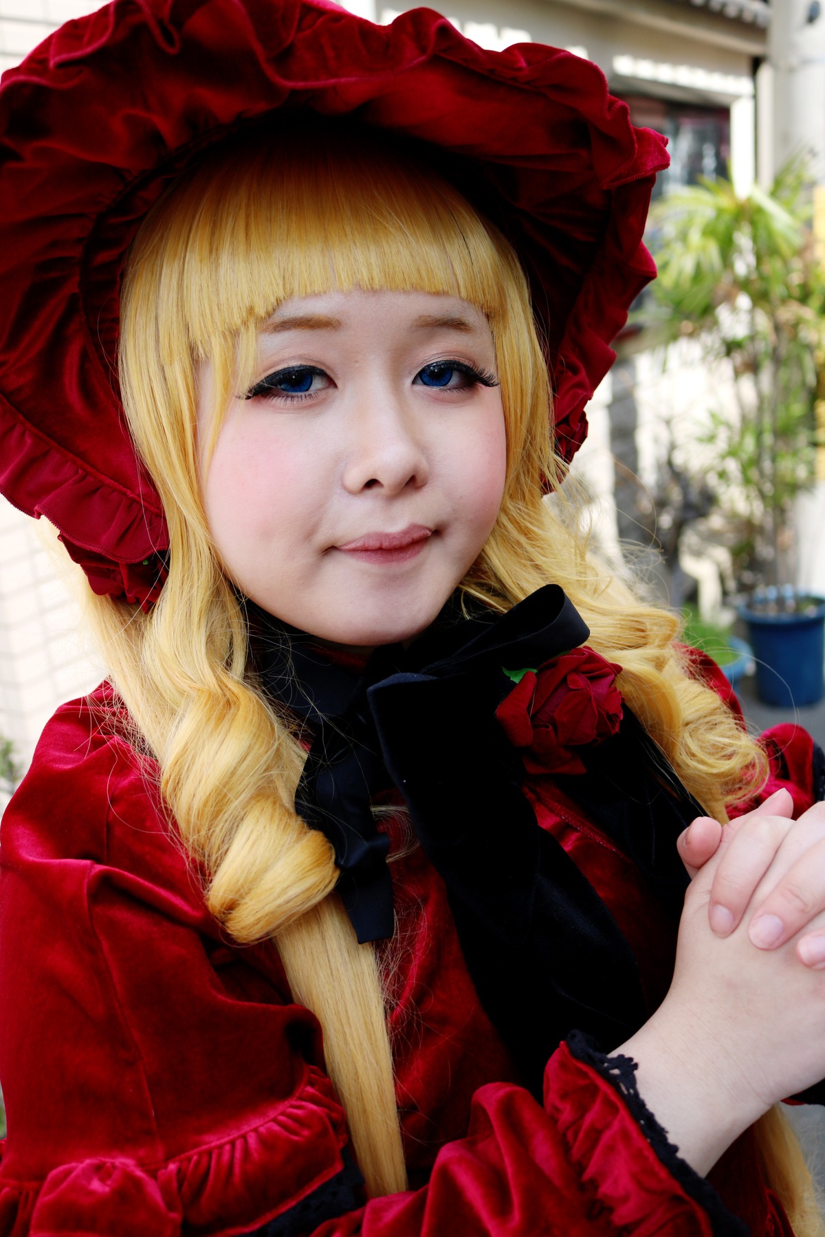 1girl bangs blonde_hair blue_eyes blurry blurry_background bonnet depth_of_field drill_hair flower frills hat lips long_hair long_sleeves looking_at_viewer photo rose shinku smile solo upper_body