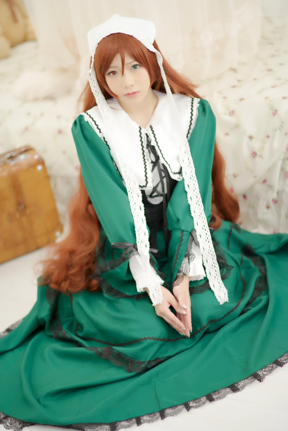1girl blurry blurry_background blurry_foreground brown_hair depth_of_field dress green_dress green_eyes lips long_hair long_sleeves looking_at_viewer sitting solo suiseiseki v_arms very_long_hair