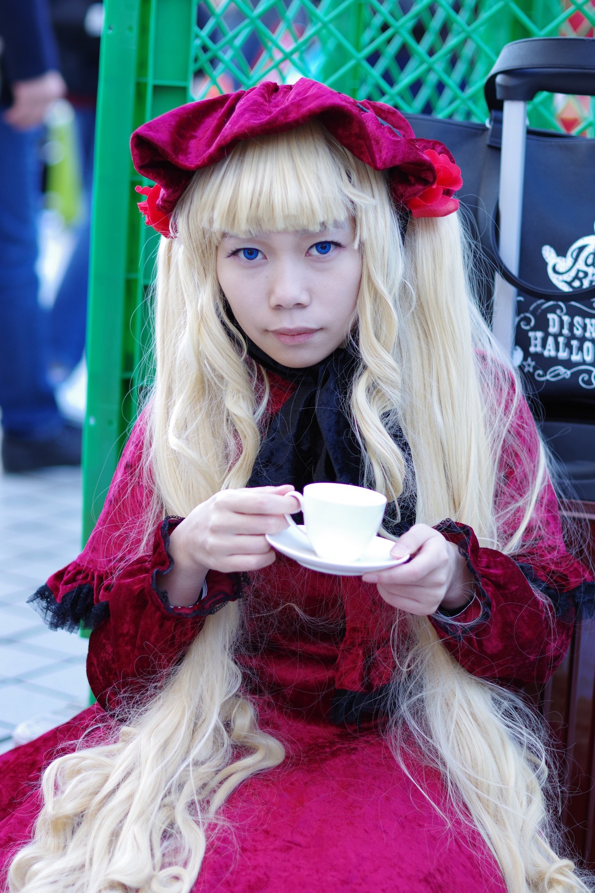 1girl bangs blonde_hair blue_eyes blunt_bangs blurry cup depth_of_field dress flower lips long_hair looking_at_viewer red_dress shinku sitting solo teacup