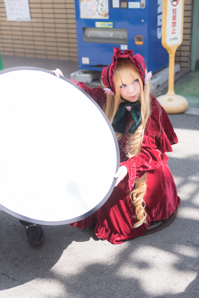 1girl bangs blonde_hair blue_eyes blurry blurry_background bonnet depth_of_field dress long_hair looking_at_viewer red_dress shinku sitting solo