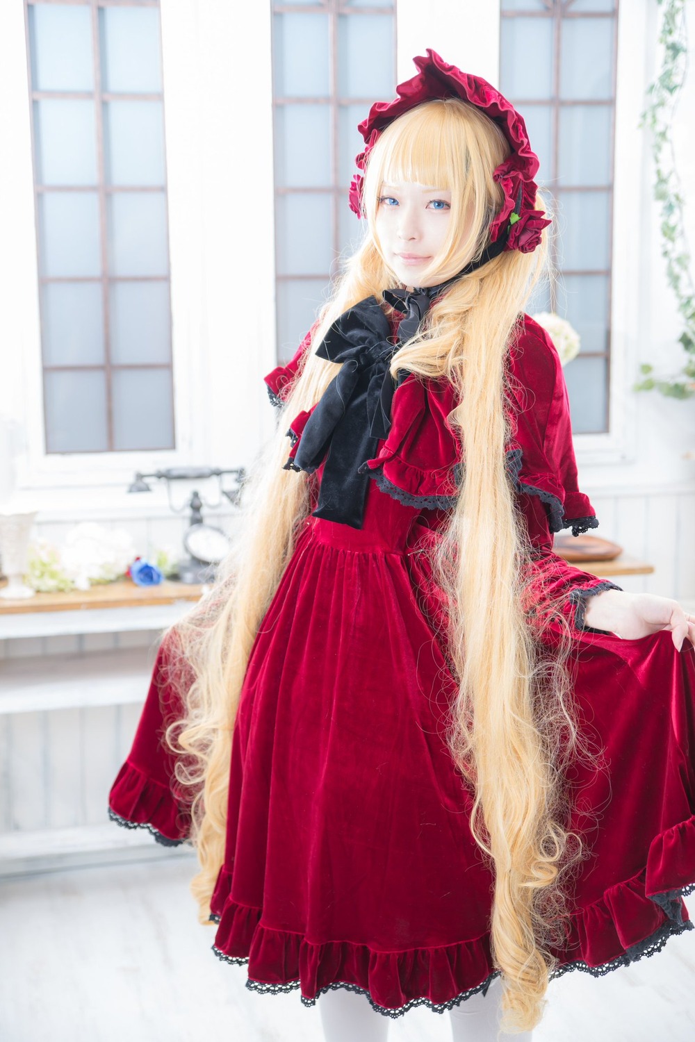 1girl blonde_hair blue_eyes blurry bonnet depth_of_field dress flower indoors long_hair looking_at_viewer red_dress shinku solo