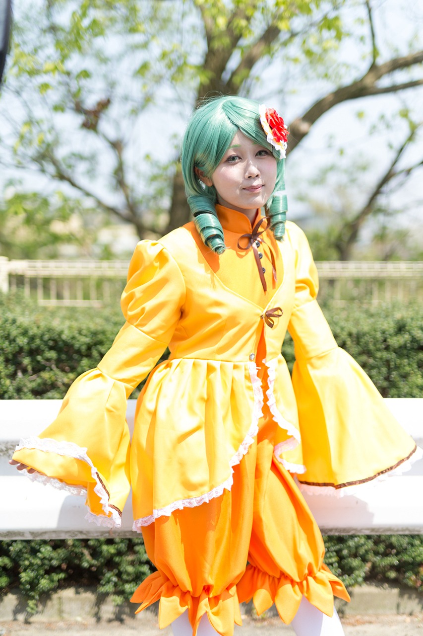 1girl blurry blurry_background blurry_foreground cherry_blossoms day depth_of_field dress flower hair_flower hair_ornament kanaria orange_dress outdoors photo solo standing tree yellow_dress