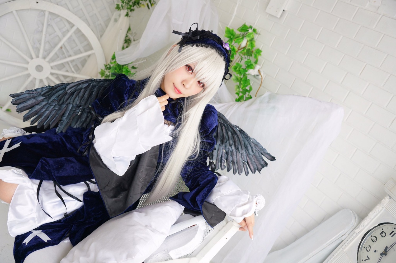 1girl angel_wings bangs dress feathered_wings feathers hairband lips long_hair long_sleeves looking_at_viewer red_eyes signature sitting solo suigintou white_hair white_wings wings