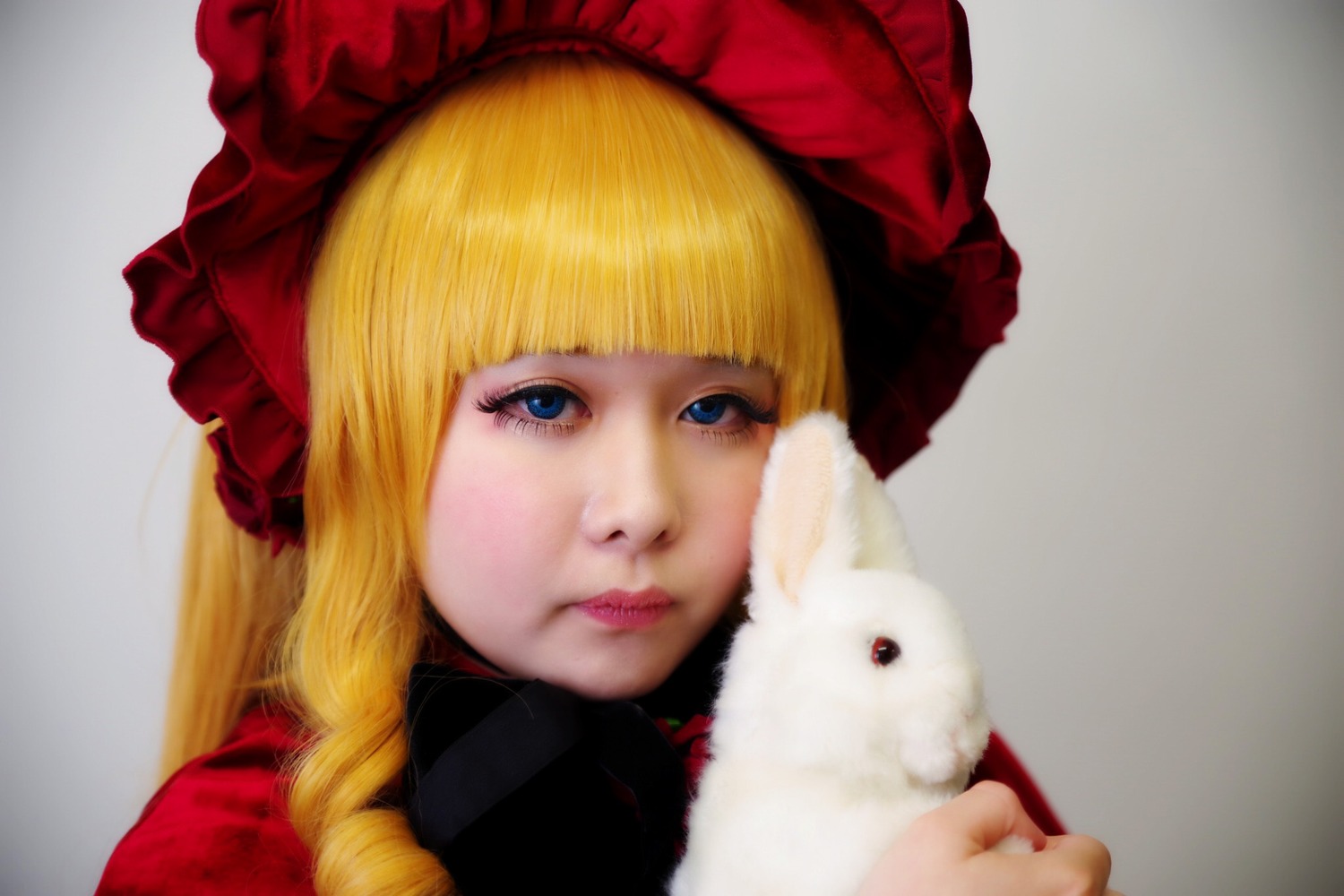 1girl animal bangs blonde_hair blue_eyes blurry bonnet bow closed_mouth depth_of_field face grey_background hat lips long_hair looking_at_viewer nose photo portrait realistic shinku simple_background solo stuffed_animal