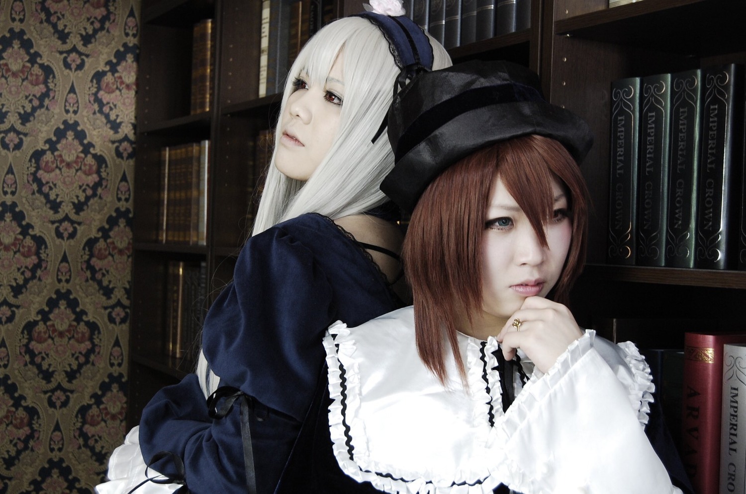 2girls bangs bookshelf brown_hair dress gothic_lolita hairband hat indoors jewelry lace lips lolita_fashion long_hair long_sleeves looking_at_viewer multiple_cosplay multiple_girls nail_polish realistic sisters tagme upper_body white_hair