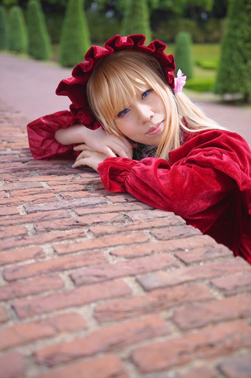 1girl blonde_hair blue_eyes blurry blurry_background blurry_foreground bonnet depth_of_field dress flower frills lips long_hair long_sleeves looking_at_viewer photo realistic red_dress shinku smile solo