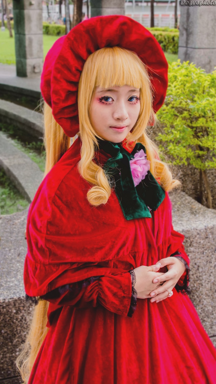 1girl bangs blonde_hair blue_eyes bonnet capelet dress flower lips long_hair looking_at_viewer outdoors own_hands_together photo realistic red_capelet red_dress shinku solo