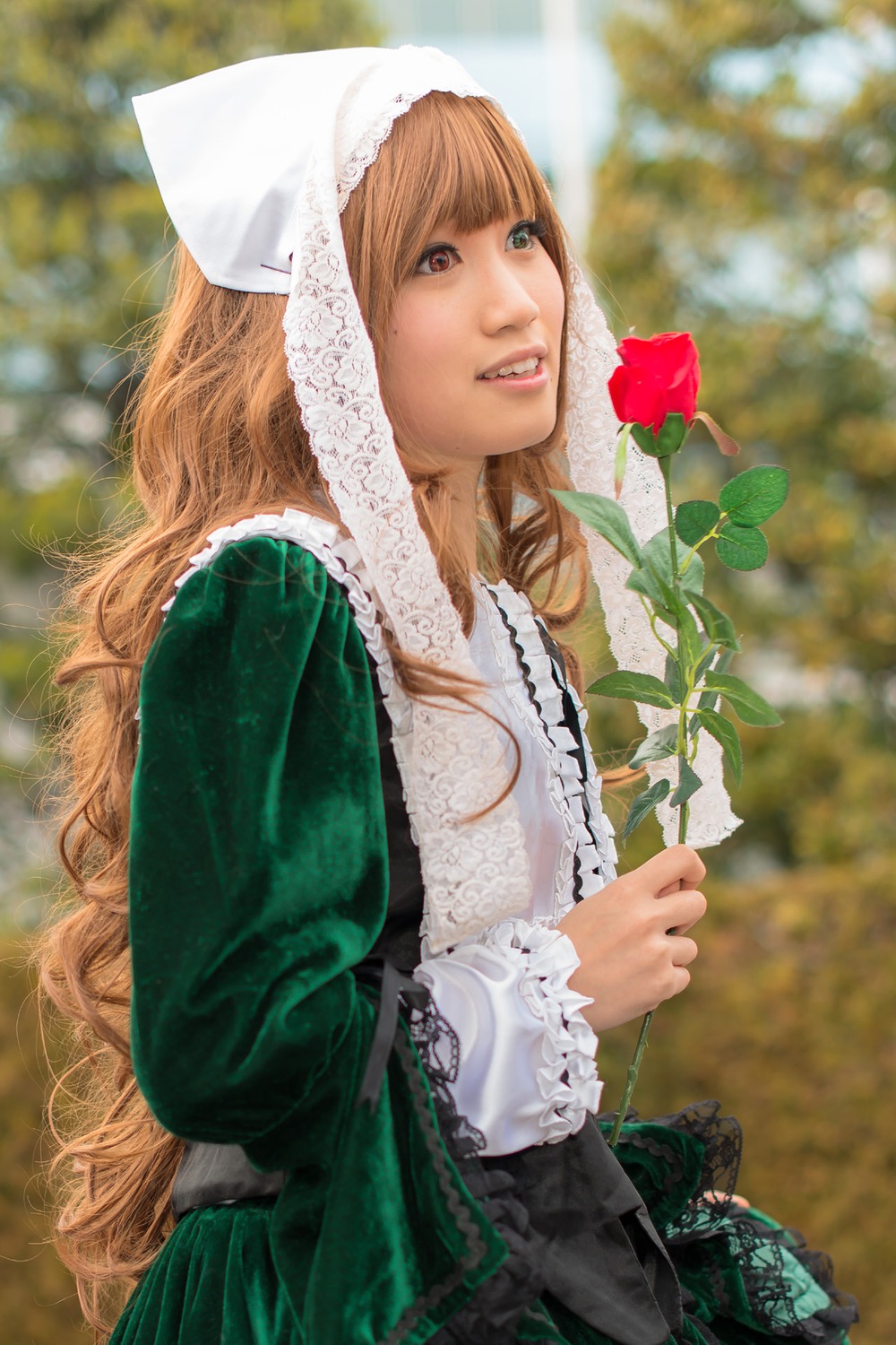 1girl blurry blurry_background brown_hair depth_of_field dress flower green_dress head_scarf lips long_hair long_sleeves outdoors solo suiseiseki