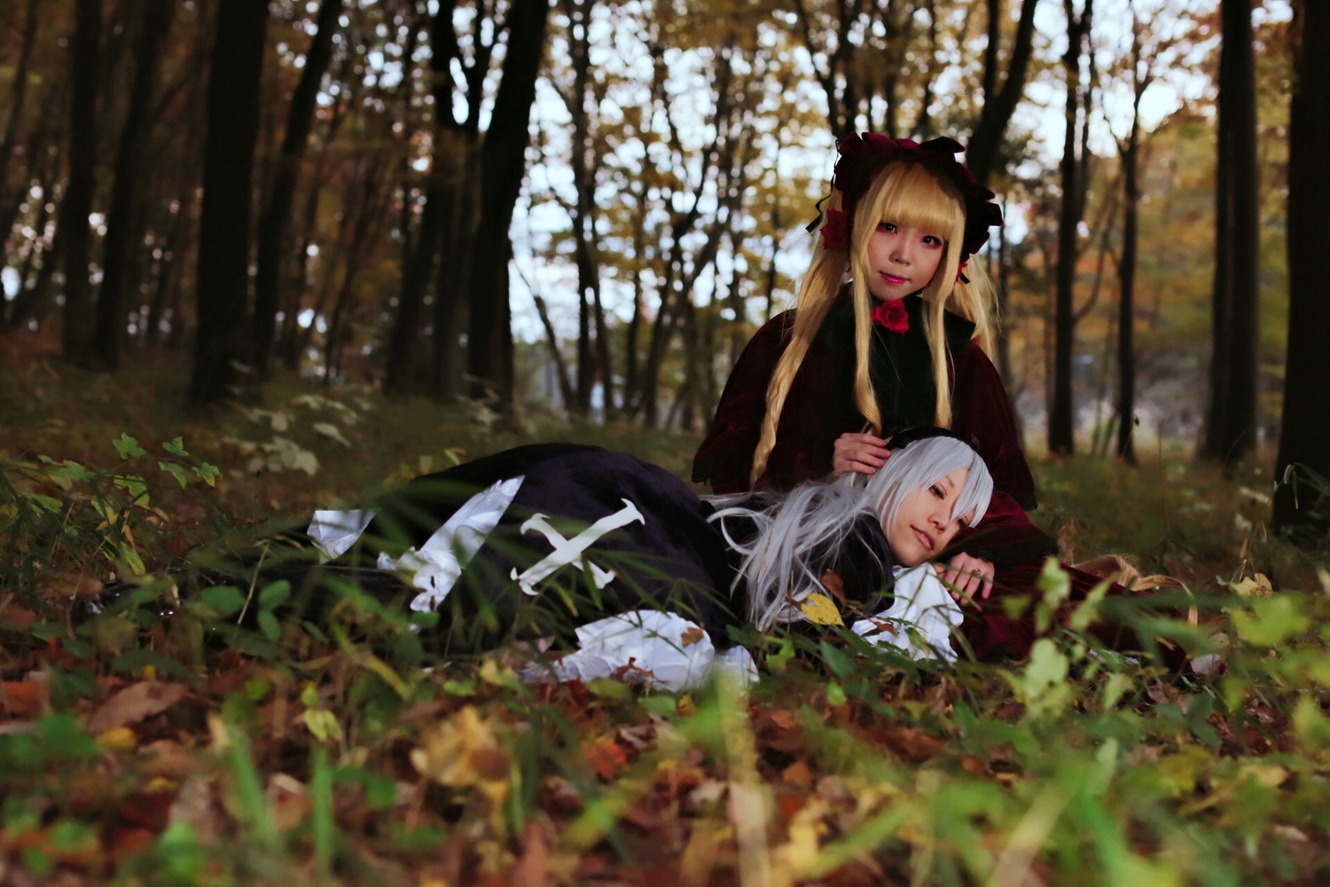 2girls blonde_hair blurry blurry_foreground day depth_of_field long_hair long_sleeves multiple_cosplay multiple_girls outdoors sunlight tagme tree