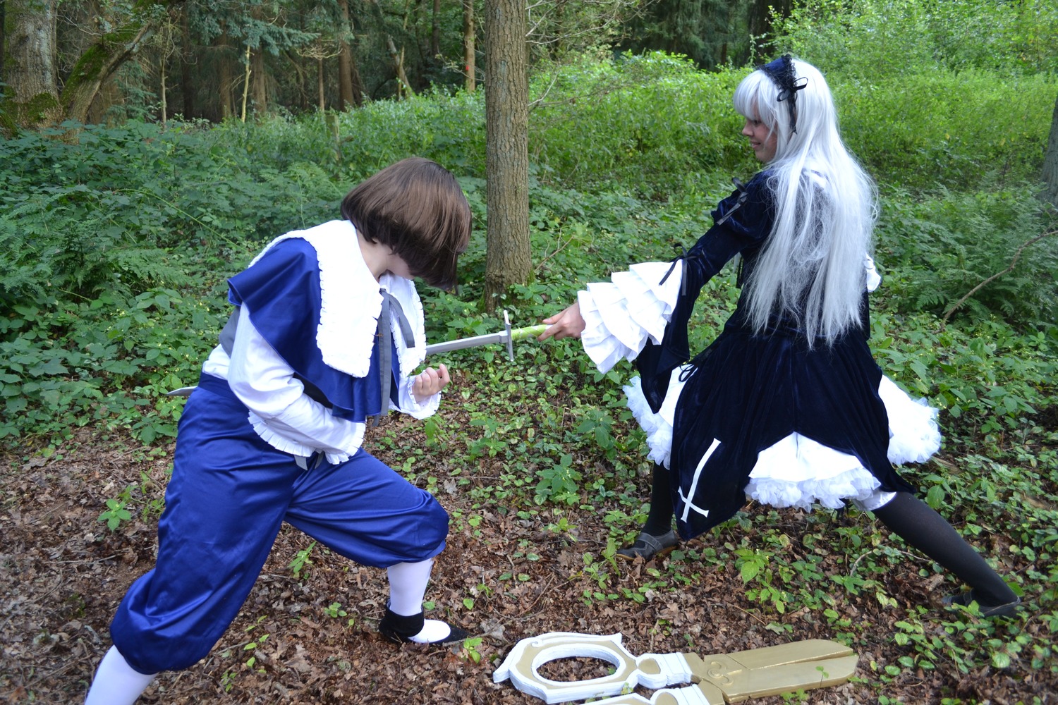 1boy 1girl brown_hair bush day dress frills grass long_hair long_sleeves multiple_cosplay outdoors sitting standing tagme tree