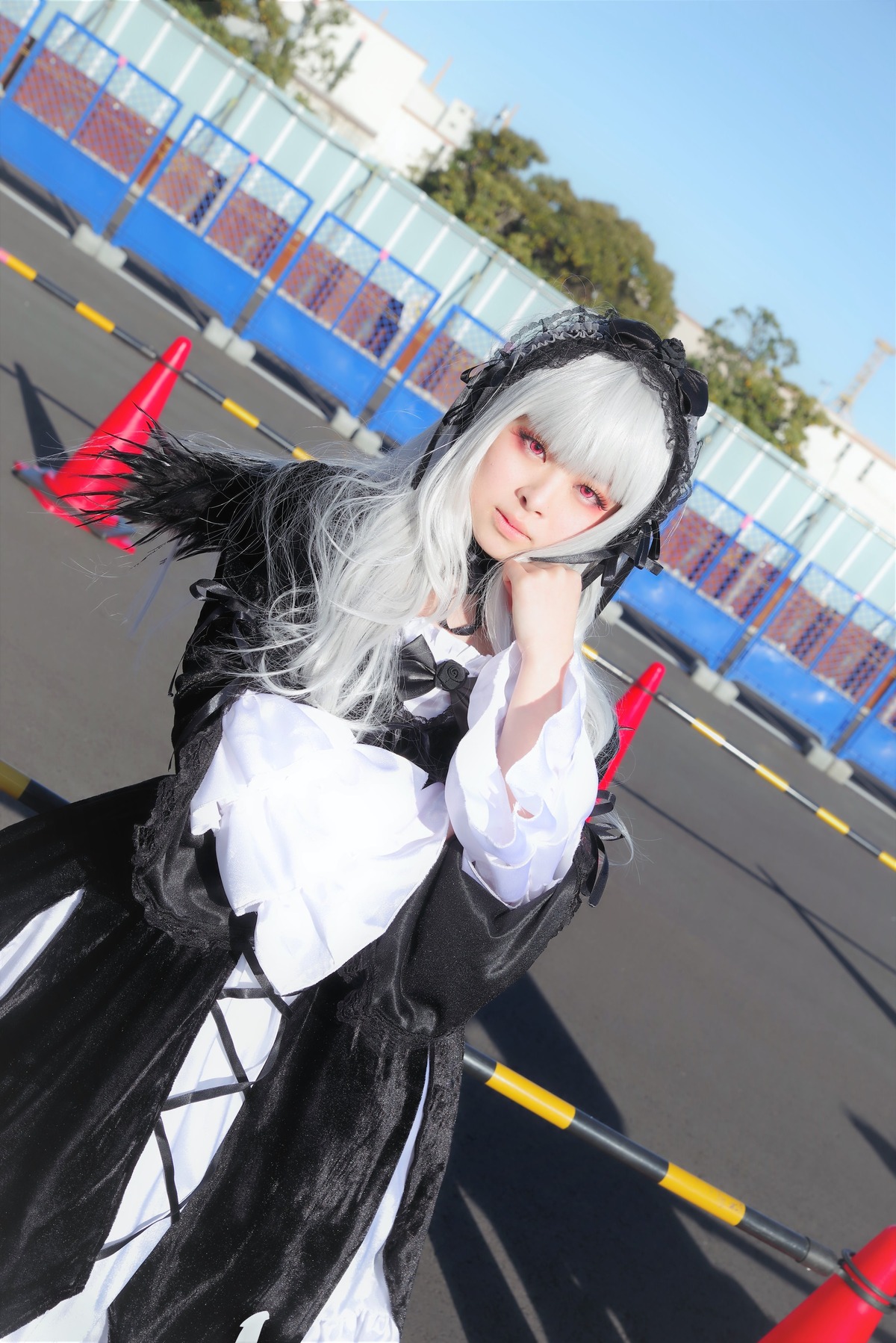 1girl black_dress building city closed_mouth day dress gothic_lolita hairband lolita_fashion long_hair long_sleeves looking_at_viewer outdoors red_eyes sky solo suigintou