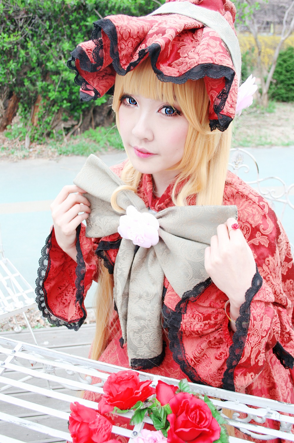 1girl blonde_hair blue_eyes bonnet building cup day flower frills garden hat lips lolita_fashion looking_at_viewer outdoors realistic red_flower red_rose rose shinku solo teacup