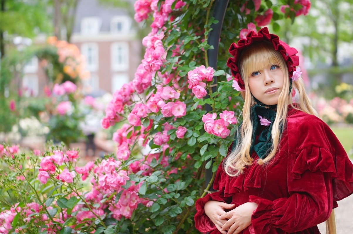 1girl bangs blonde_hair blue_eyes blurry blurry_background blurry_foreground bonnet day depth_of_field dress flower garden lips long_hair long_sleeves looking_at_viewer outdoors pink_flower pink_rose shinku solo