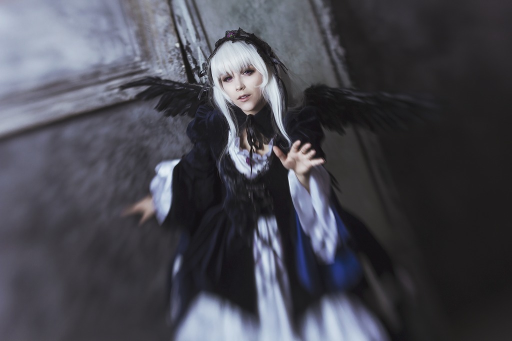 1girl black_dress black_wings blurry blurry_background depth_of_field dress lips long_hair long_sleeves looking_at_viewer ribbon rose silver_hair solo standing suigintou wide_sleeves wings