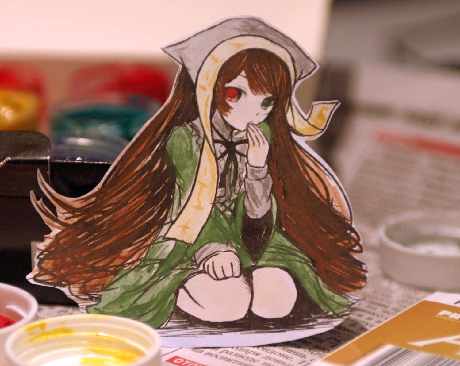 1girl blurry blurry_background blurry_foreground brown_hair depth_of_field dress food frills green_dress green_eyes heterochromia highres image imageboard_desourced long_hair long_sleeves looking_at_viewer non-web_source paper_child papercraft_(medium) photo photo_(medium) red_eyes rozen_maiden sitting solo suiseiseki traditional_media unconventional_media very_long_hair