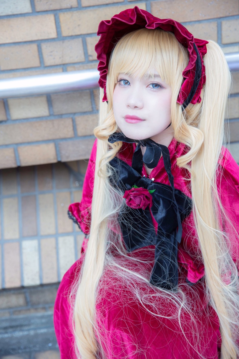 1girl blonde_hair blue_eyes blurry blurry_background brick_wall depth_of_field dress flower lips lolita_fashion long_hair looking_at_viewer photo pink_rose red_flower red_rose rose shinku solo