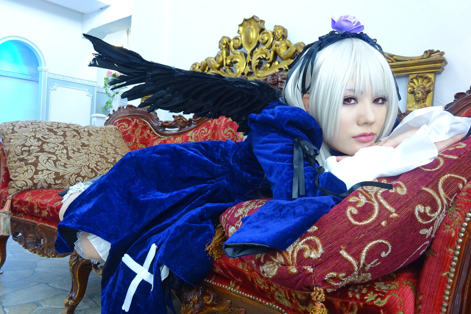 1girl couch dress feathers flower frills hairband indoors lips long_sleeves lying on_side on_stomach red_eyes solo suigintou white_hair wings