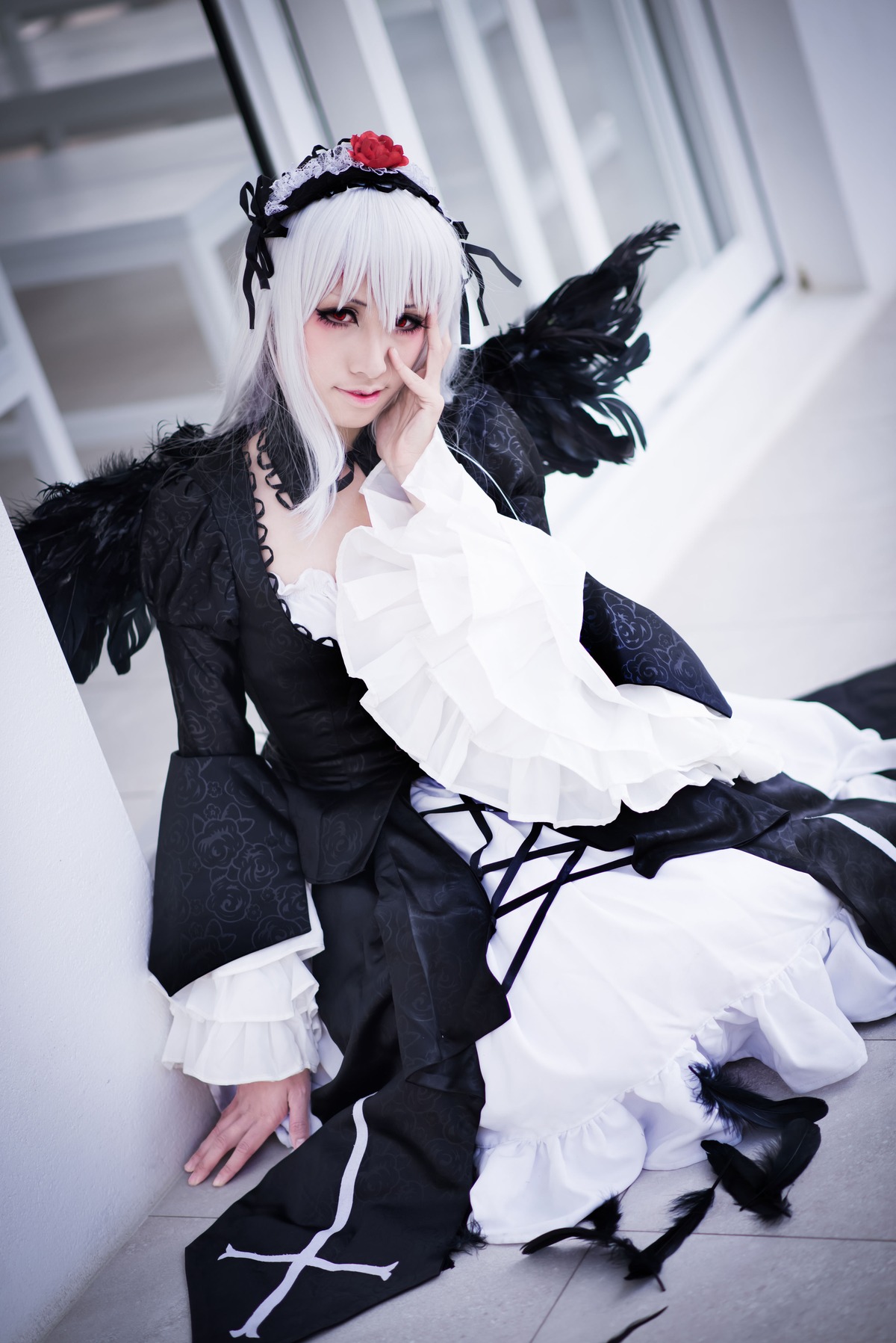 1girl black_dress dress feathers flower frills gothic_lolita hairband indoors lolita_fashion long_hair long_sleeves looking_at_viewer silver_hair sitting solo suigintou