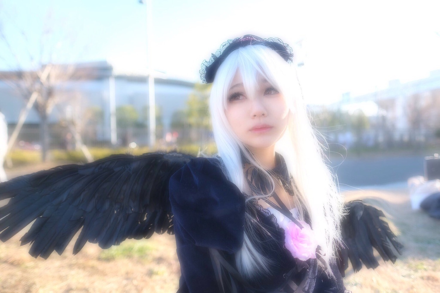 1girl black_wings blurry blurry_background building closed_mouth depth_of_field dress feathered_wings feathers lips long_hair solo suigintou upper_body wings