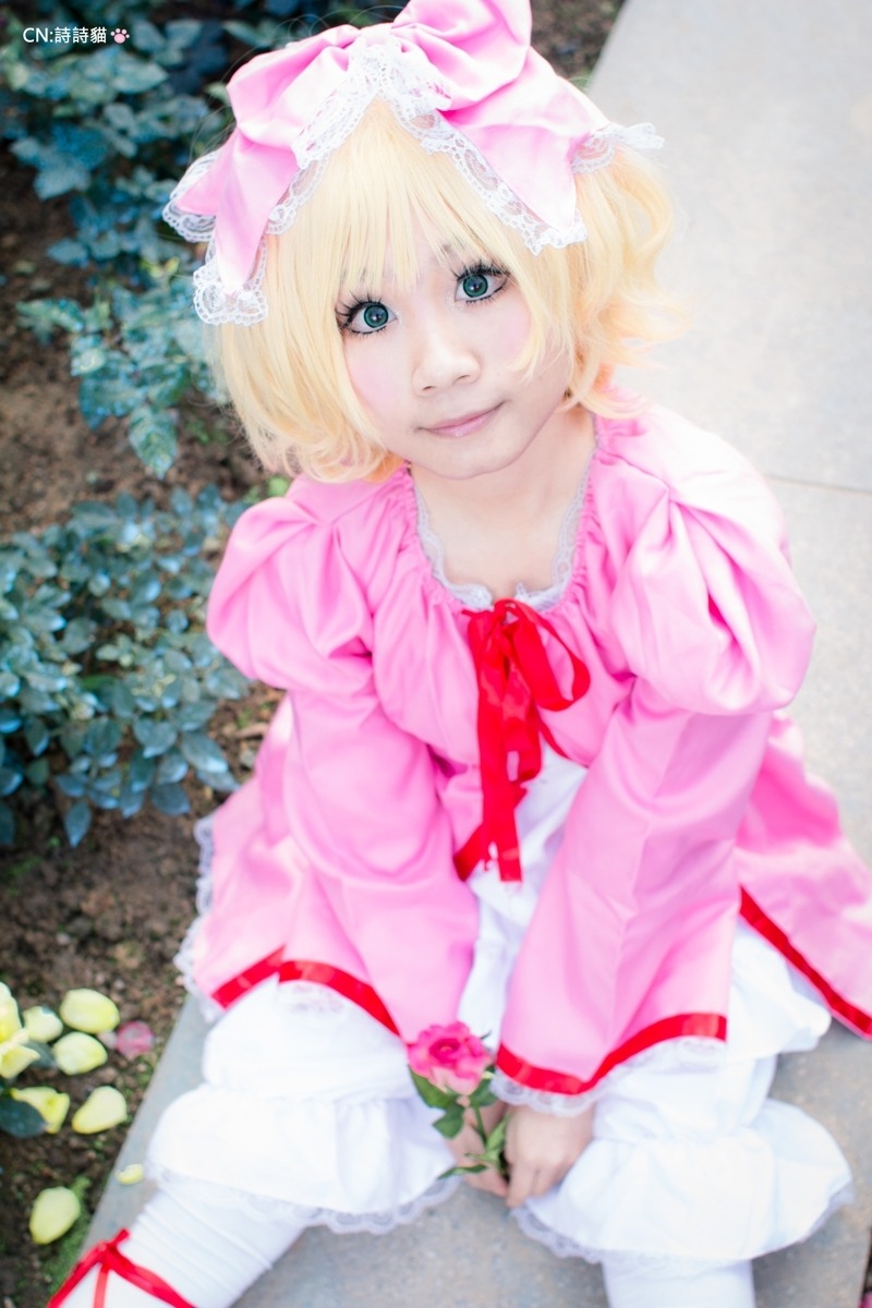 1girl blonde_hair blue_eyes blurry blurry_background bow depth_of_field dress flower frills hinaichigo lips long_sleeves looking_at_viewer outdoors photo pink_dress realistic ribbon short_hair sitting smile solo