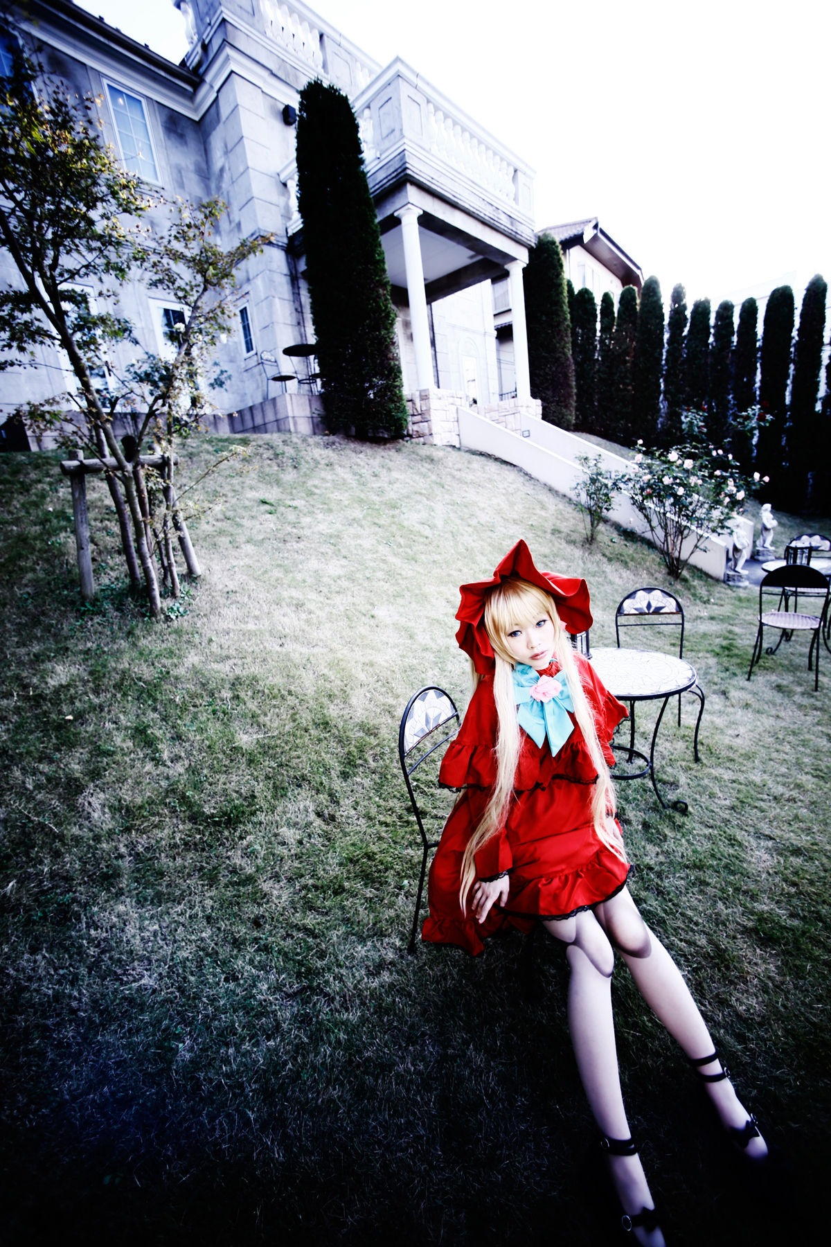 1girl blonde_hair blue_eyes bow building dress hair_bow lamppost long_hair long_sleeves outdoors red_dress shinku shoes solo standing tree white_legwear