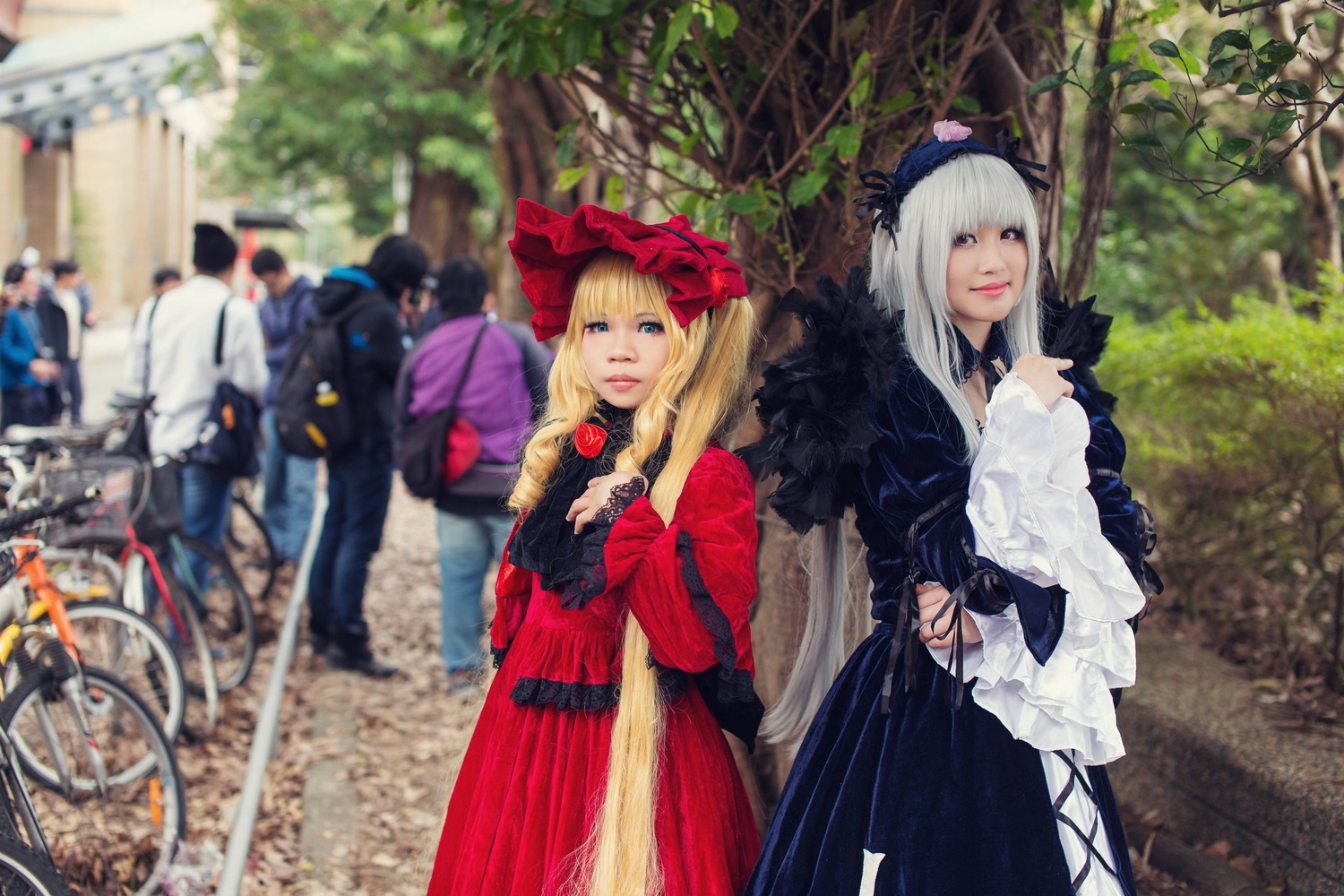 blonde_hair blue_eyes blurry blurry_background blurry_foreground depth_of_field dress hat long_hair long_sleeves multiple_cosplay multiple_girls outdoors photo standing tagme