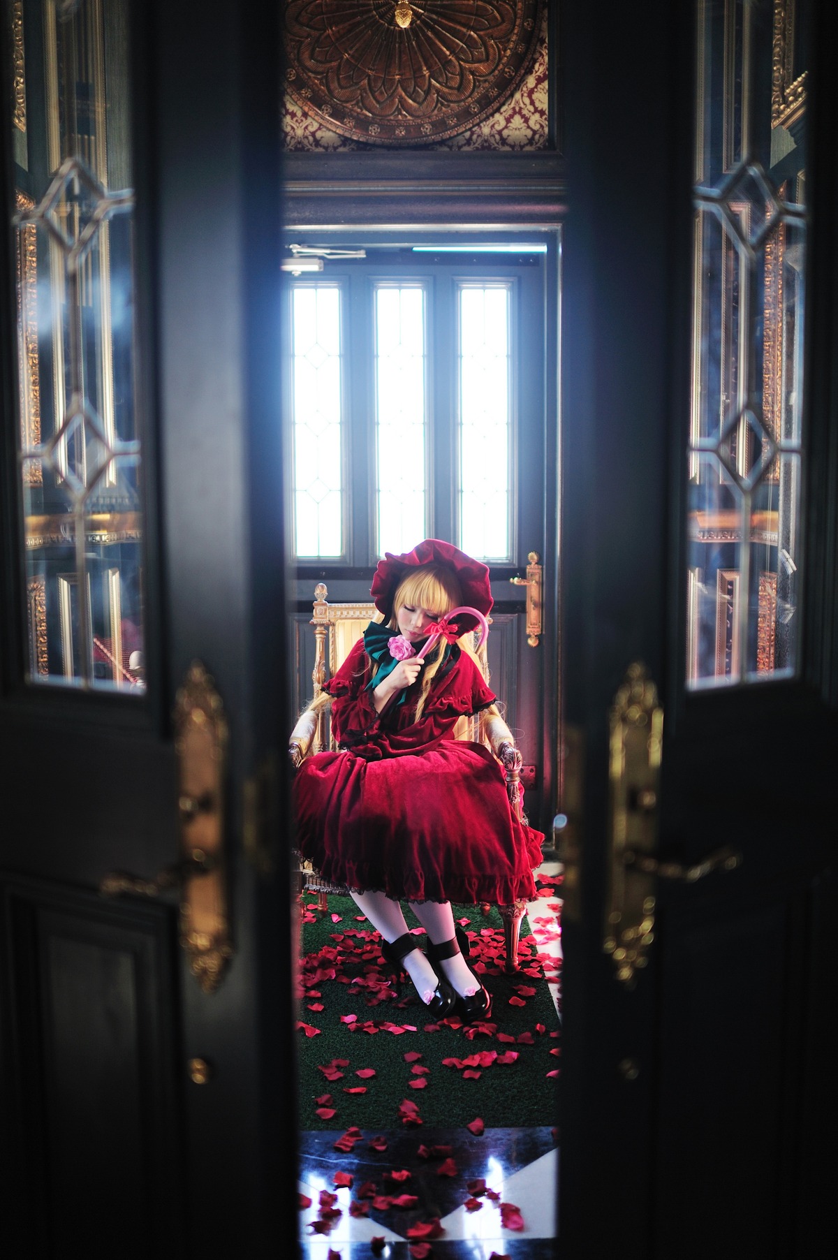 1girl blonde_hair blurry blurry_background blurry_foreground bonnet depth_of_field dress flower frills indoors red_dress shinku shoes solo standing window wrist_cuffs