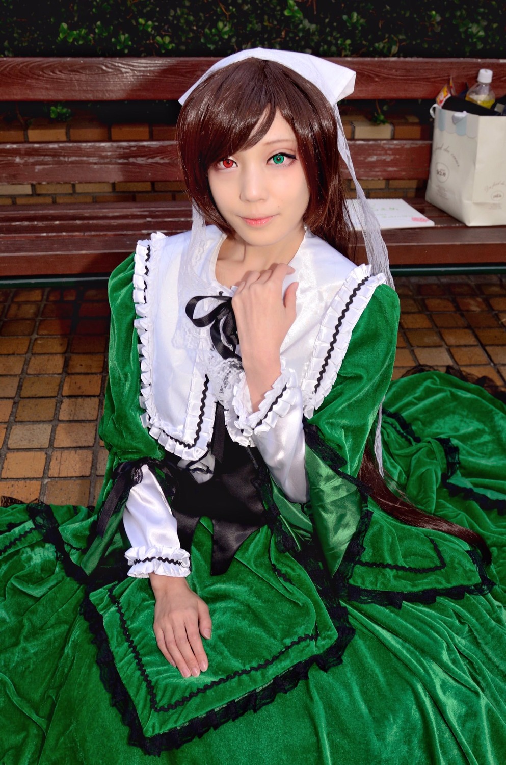 1girl brown_hair closed_mouth dress frills green_dress green_eyes heterochromia long_sleeves looking_at_viewer red_eyes sitting smile solo suiseiseki