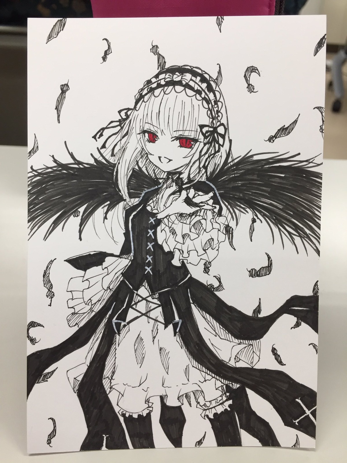 1girl black_feathers dress feathered_wings feathers frilled_hairband frills gothic_lolita greyscale hairband image lolita_fashion lolita_hairband long_sleeves looking_at_viewer monochrome open_mouth photo red_eyes smile solo suigintou traditional_media white_feathers wings