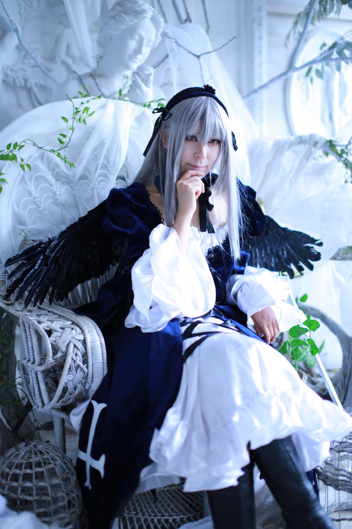 1girl blurry blurry_background blurry_foreground depth_of_field dress feathers flower hairband long_hair long_sleeves silver_hair sitting solo suigintou very_long_hair wings