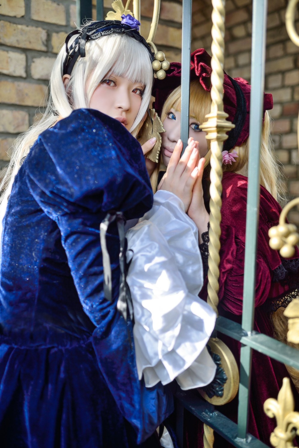 2girls bangs blonde_hair blue_eyes blurry depth_of_field dress frills hairband hug indoors lolita_fashion long_hair long_sleeves looking_at_viewer multiple_cosplay multiple_girls red_eyes shinku sitting tagme white_hair