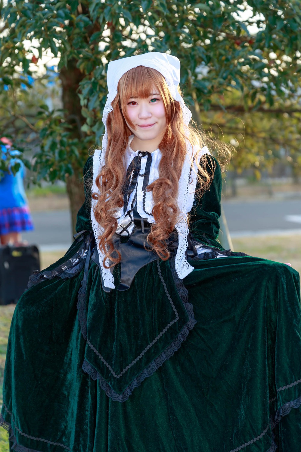 1girl blue_eyes blurry blurry_background brown_hair depth_of_field dress green_eyes long_hair long_sleeves looking_at_viewer sitting smile solo suiseiseki