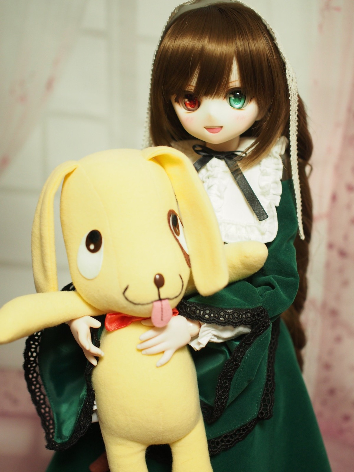 1girl :d blurry brown_hair doll dress frills green_dress green_eyes heterochromia holding long_hair long_sleeves looking_at_viewer open_mouth red_eyes smile solo stuffed_animal suiseiseki