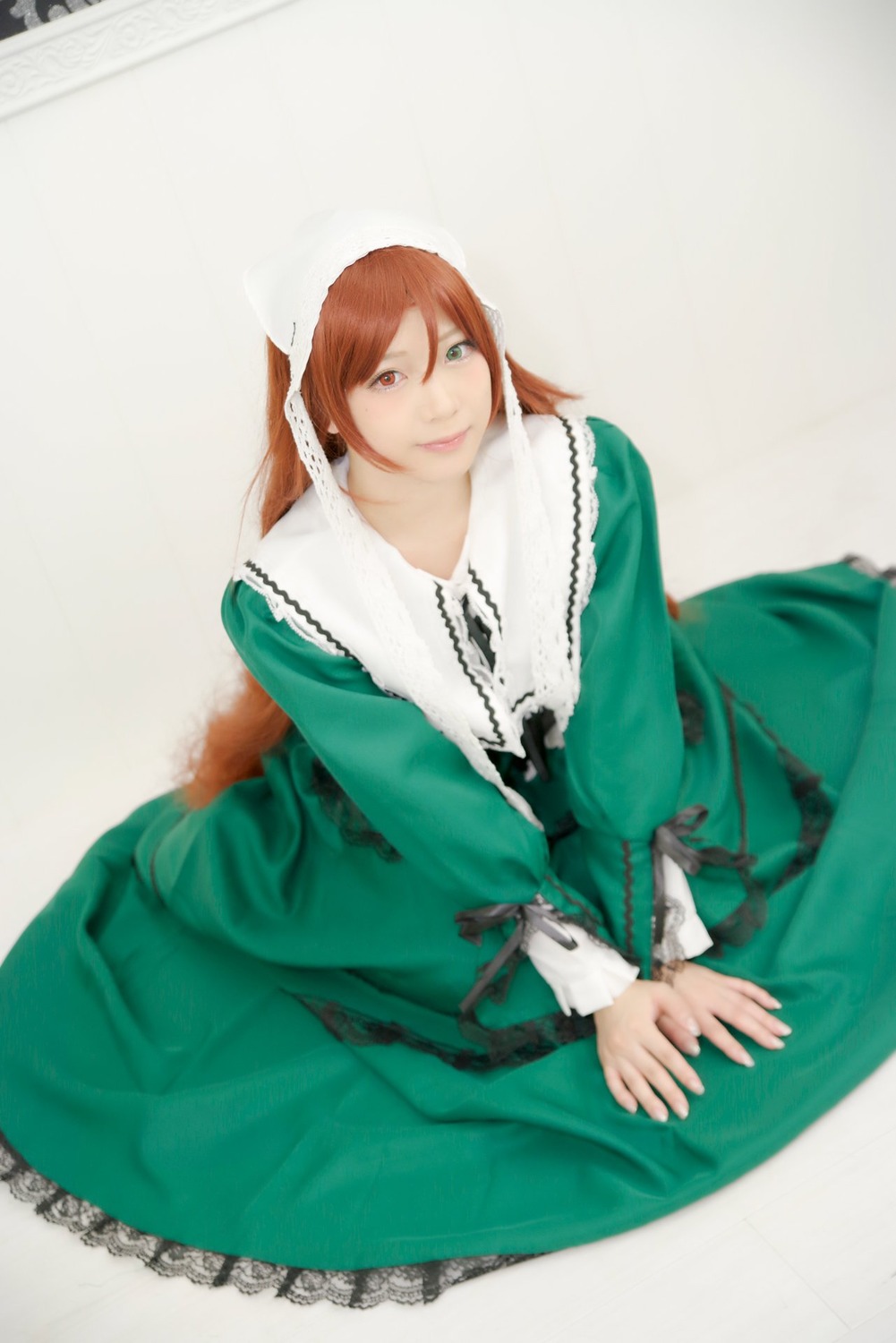 1girl brown_hair dress green_dress heterochromia lips long_sleeves looking_at_viewer sitting smile solo suiseiseki