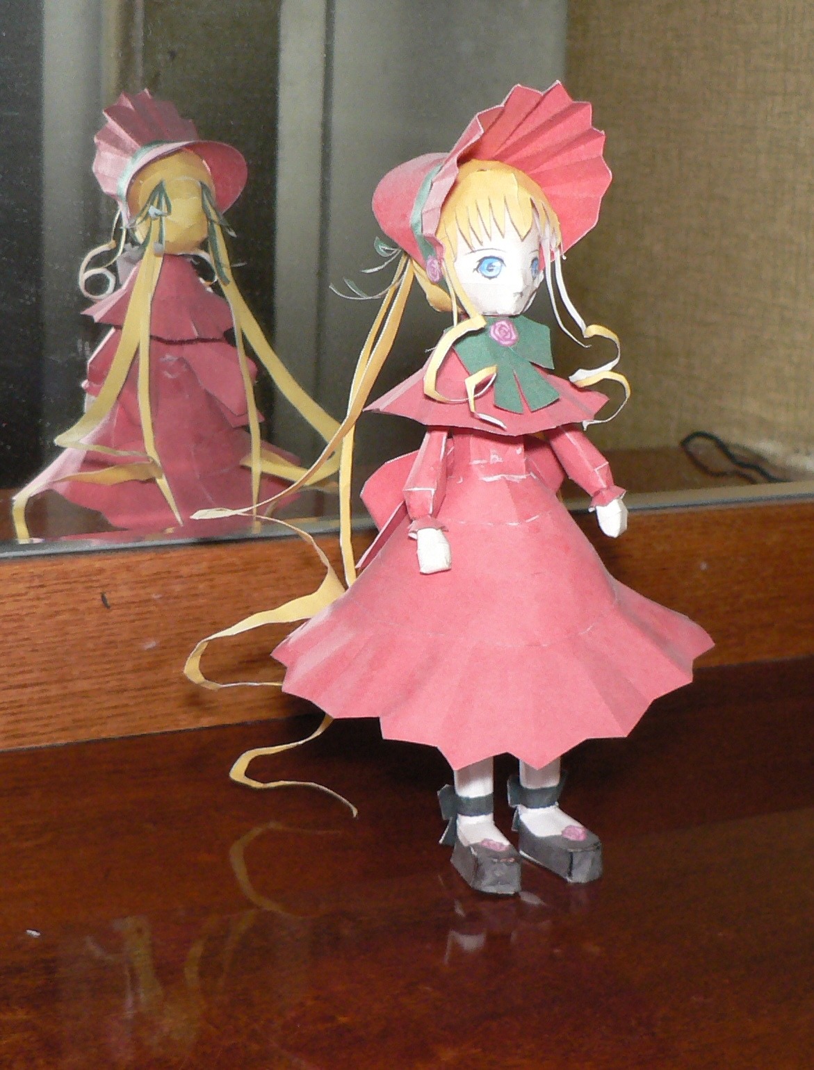 1girl blonde_hair blue_eyes bonnet bow bowtie doll dress full_body hat indoors long_hair long_sleeves looking_at_viewer photo red_dress reflection shinku sidelocks solo standing twintails very_long_hair