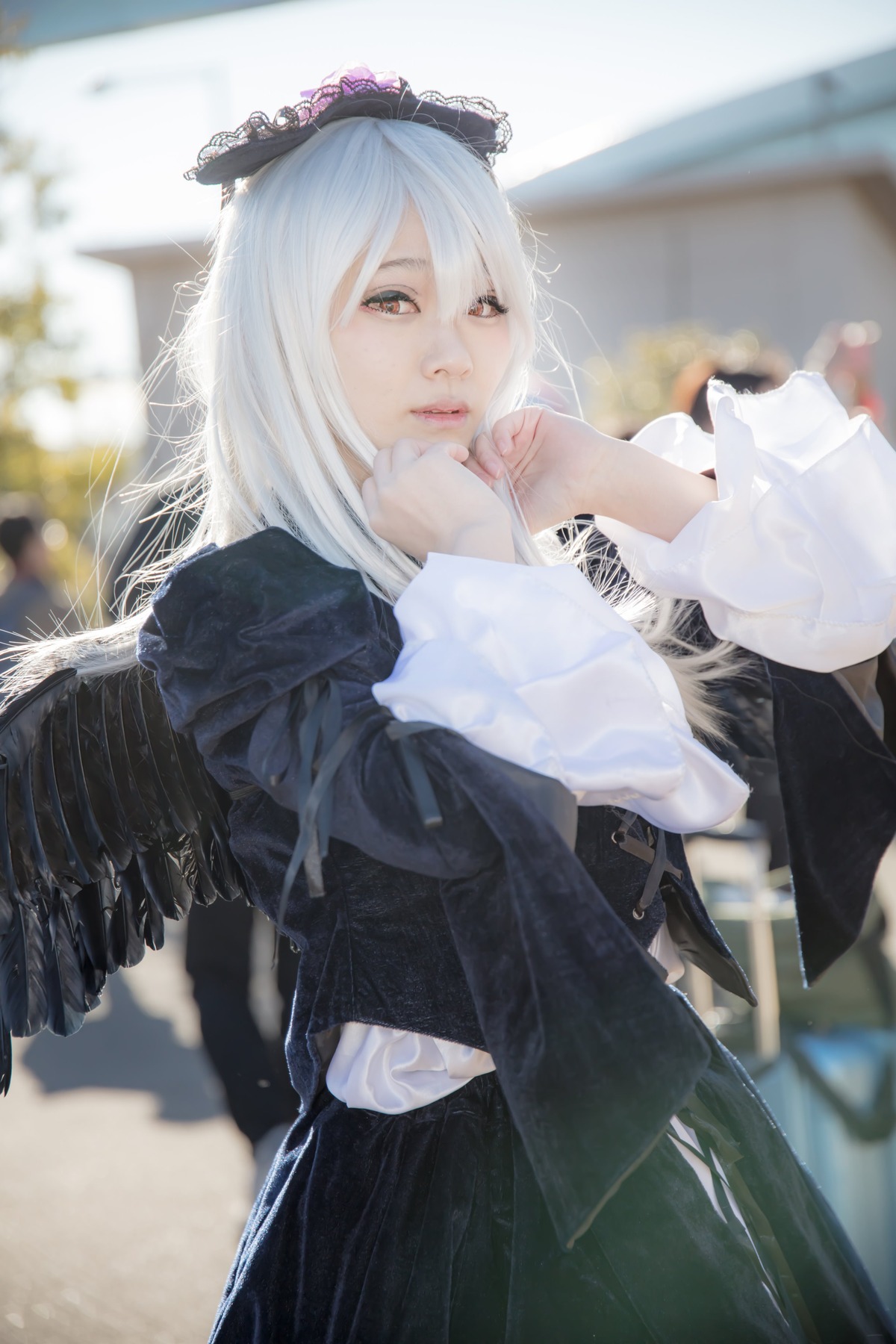 1girl angel angel_wings black_wings blurry blurry_background blurry_foreground closed_mouth depth_of_field feathered_wings feathers lips long_hair long_sleeves looking_at_viewer photo solo suigintou white_wings wings