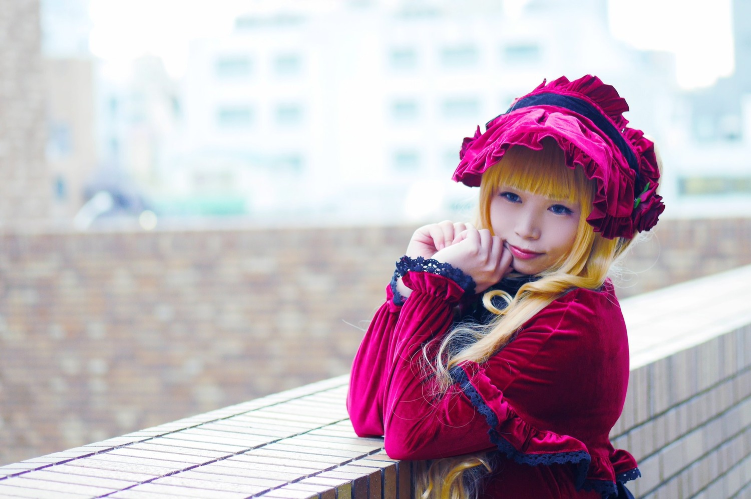 1girl bangs blonde_hair blue_eyes blurry bonnet capelet depth_of_field dress frills long_hair long_sleeves outdoors red_capelet shinku smile solo upper_body