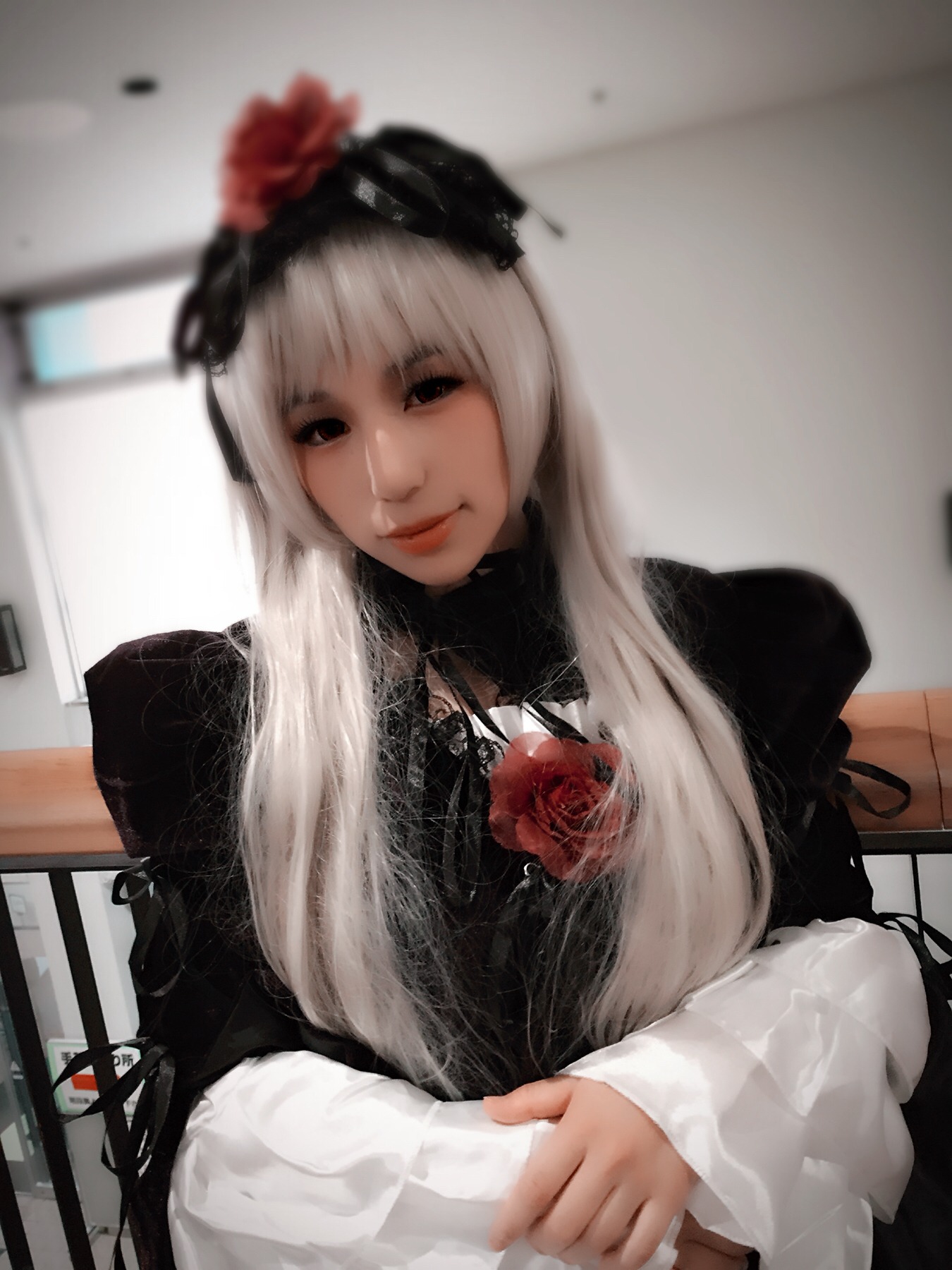 1girl bangs blurry blurry_background closed_mouth depth_of_field dress flower hair_ornament indoors lips long_hair long_sleeves looking_at_viewer photo red_flower red_rose rose solo suigintou table upper_body white_hair