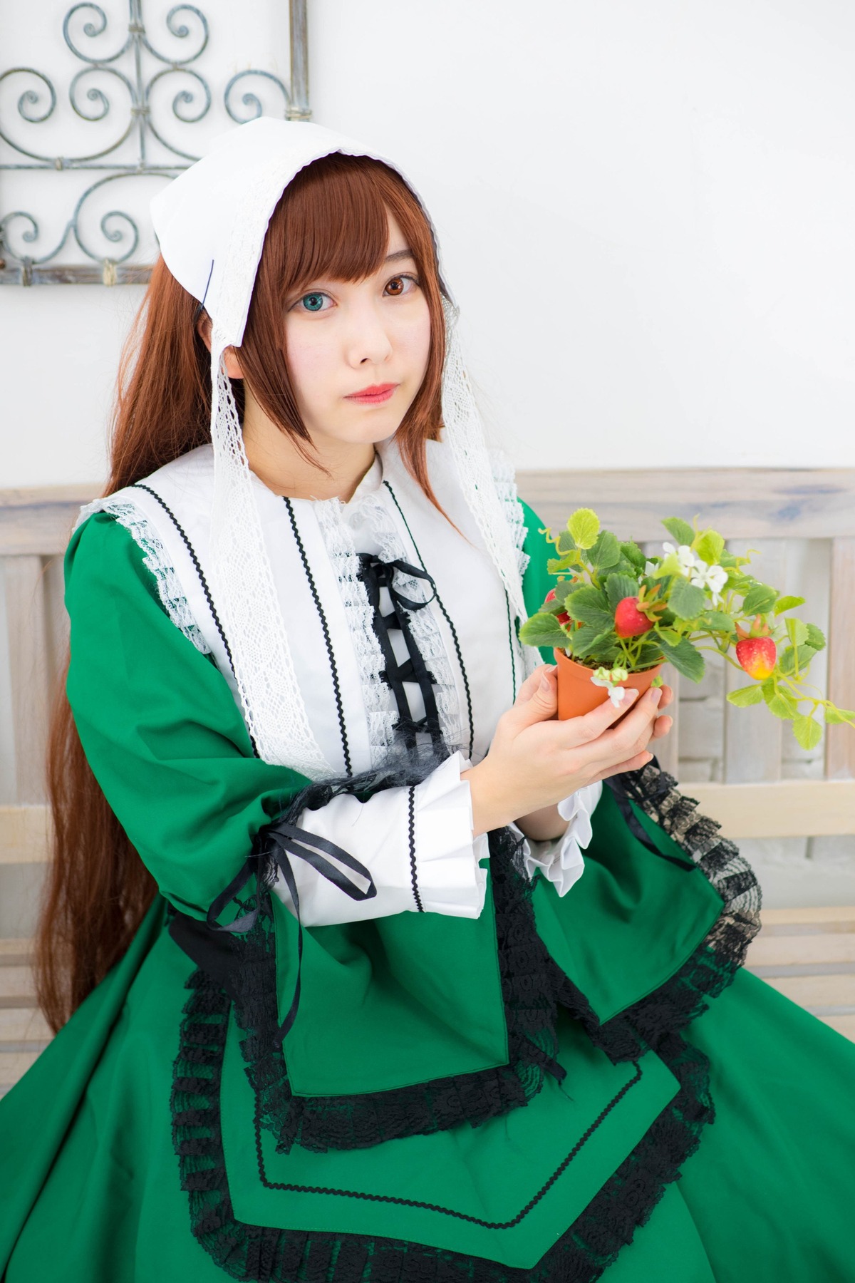 1girl bangs blue_eyes brown_hair dress flower green_dress heterochromia holding holding_flower lips long_hair long_sleeves looking_at_viewer solo standing suiseiseki