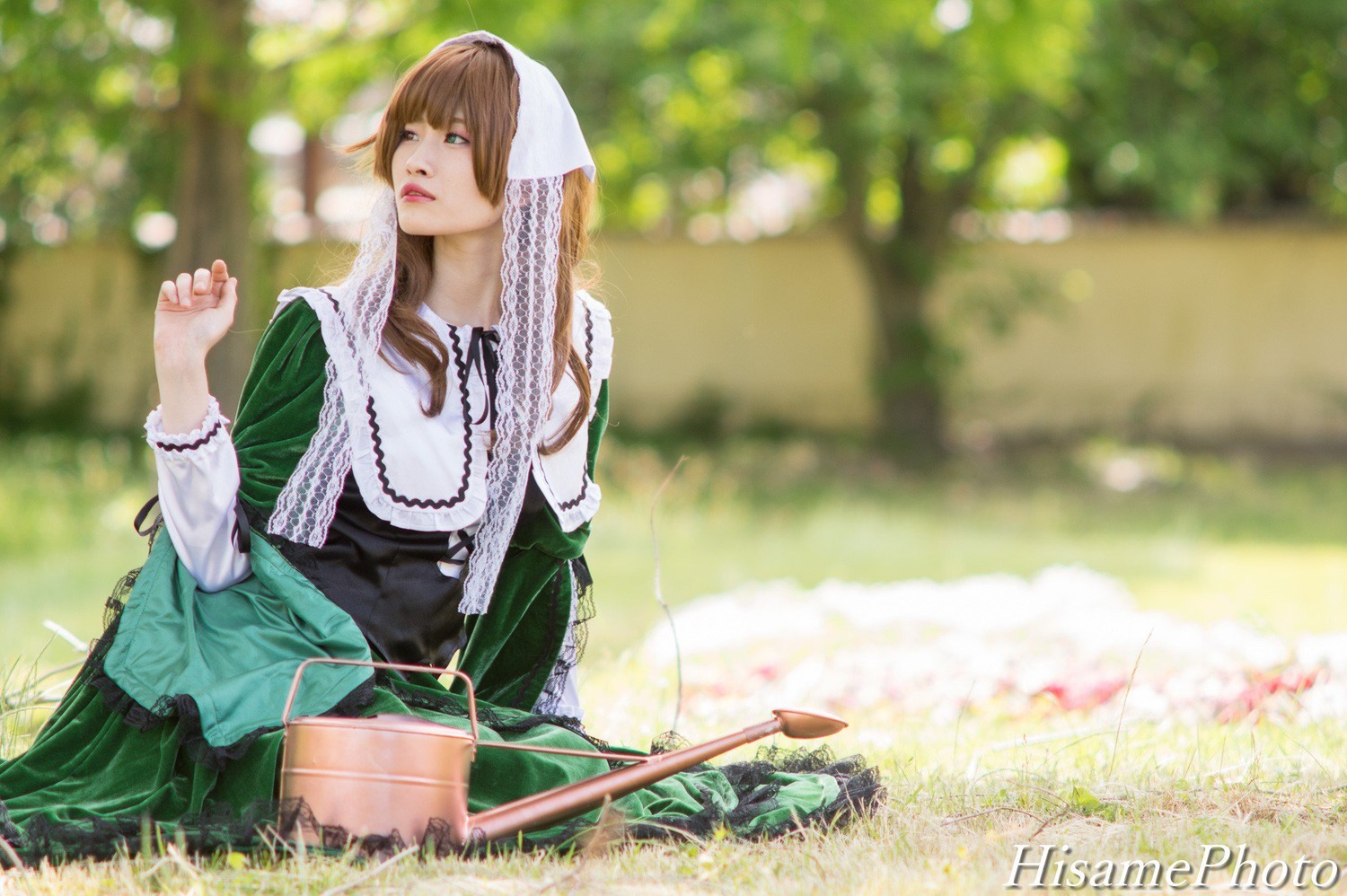 1girl blue_eyes blurry blurry_background blurry_foreground brown_hair cloak depth_of_field dress grass green_dress green_eyes hood lips outdoors solo suiseiseki watermark