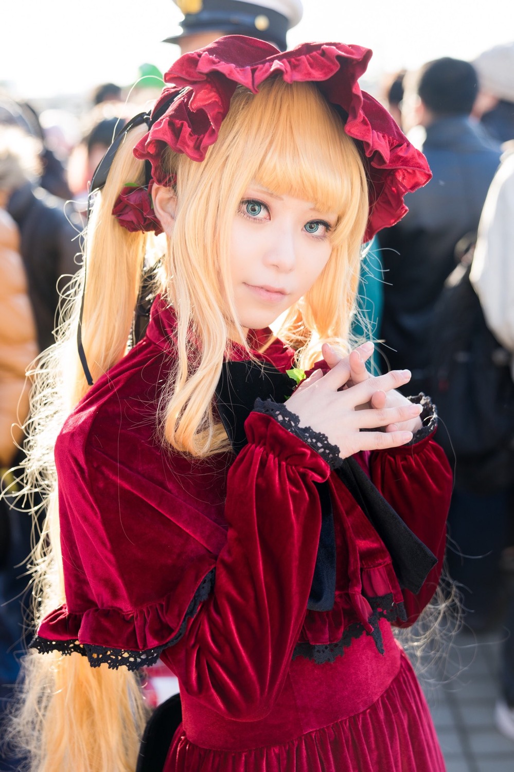 1girl bangs blonde_hair blue_eyes blurry blurry_background blurry_foreground capelet depth_of_field dress flower frills lace long_hair looking_at_viewer photo red_capelet shinku solo solo_focus