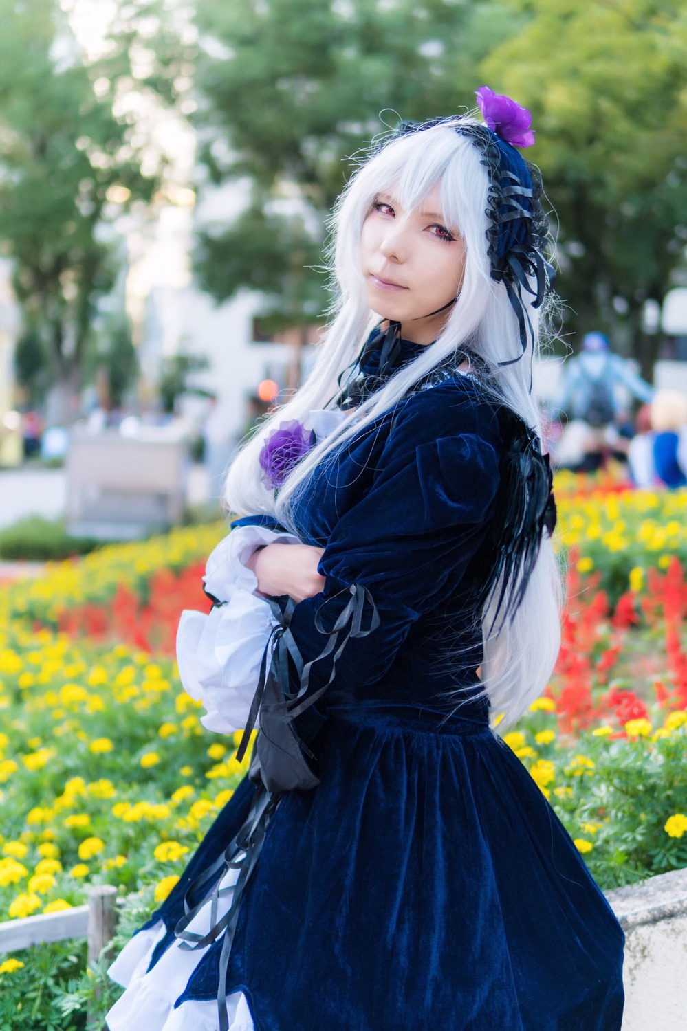 1girl blurry blurry_background blurry_foreground depth_of_field flower long_hair looking_at_viewer outdoors photo red_eyes skirt solo suigintou white_hair