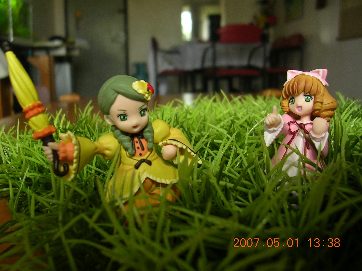 2girls blonde_hair blurry bow depth_of_field doll dress flower grass green_eyes hair_ornament hina_ichigo multiple_dolls multiple_girls open_mouth pink_bow short_hair tagme