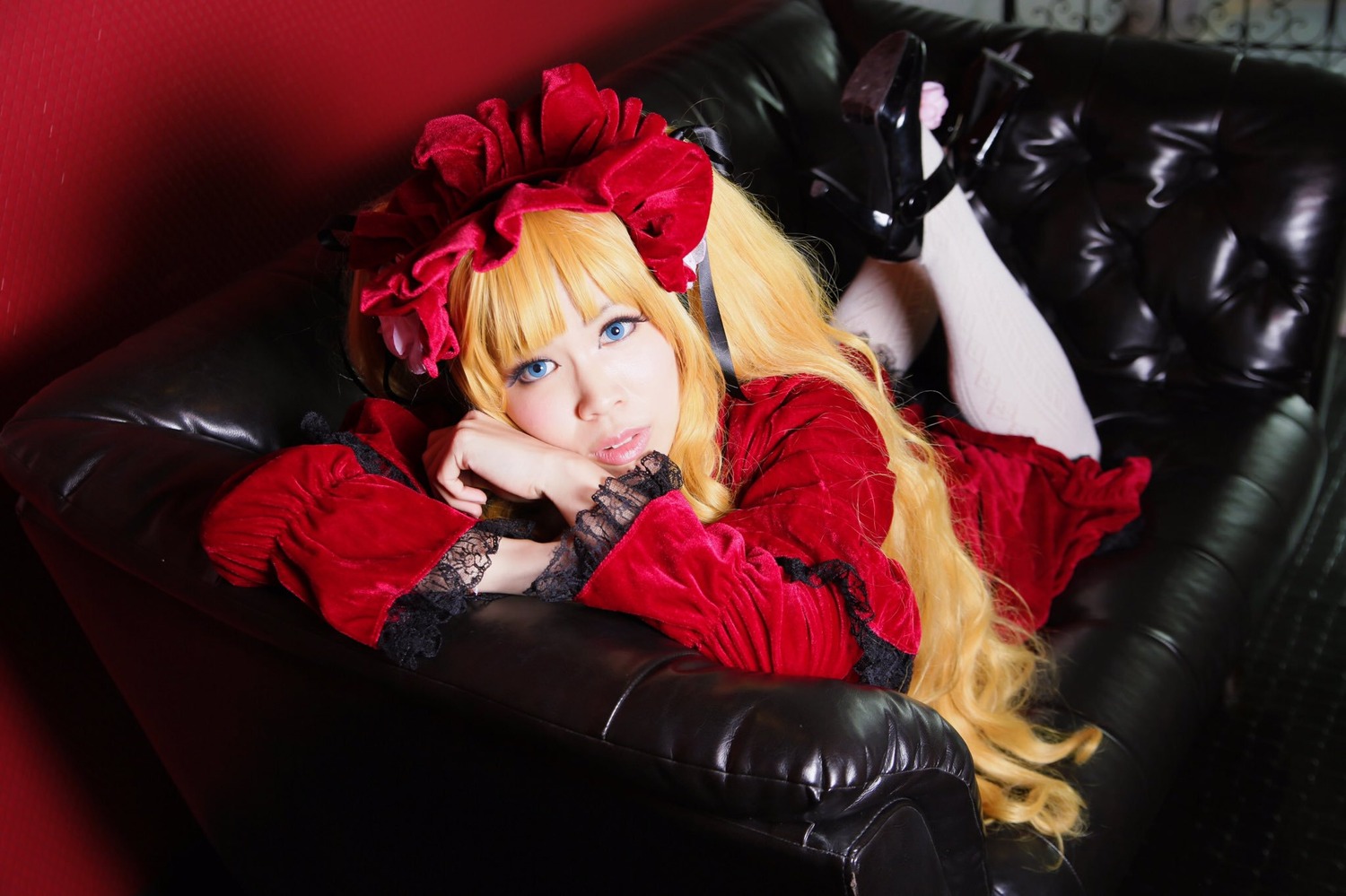 1girl blonde_hair blue_eyes bonnet bow couch dress flower frills gothic_lolita lips lolita_fashion long_hair long_sleeves looking_at_viewer lying on_stomach red_dress rose shinku solo twintails