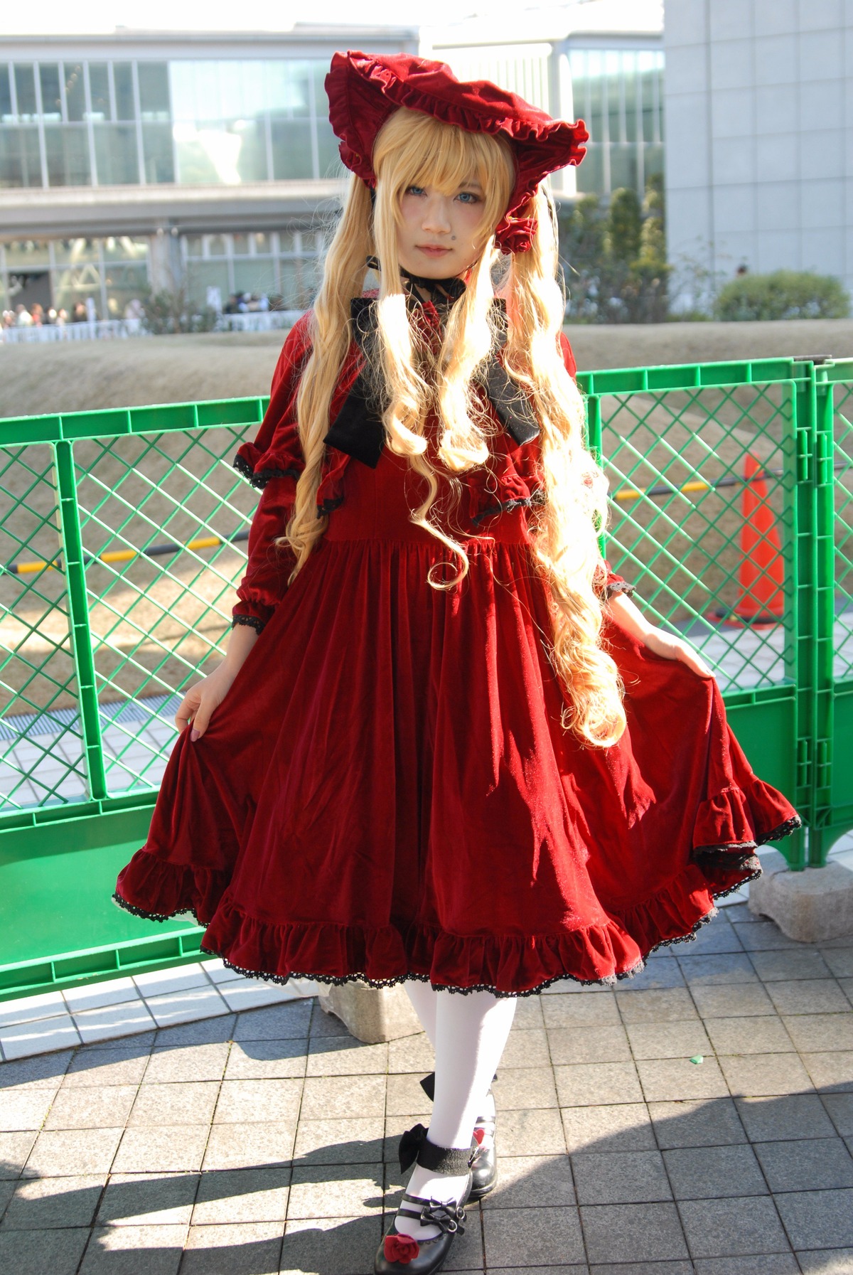 1girl blonde_hair bonnet chain-link_fence day dress fence honeycomb_(pattern) honeycomb_background lolita_fashion long_hair long_sleeves looking_at_viewer pantyhose pavement red_dress rooftop shinku shoes solo standing tile_floor tile_wall tiles white_legwear