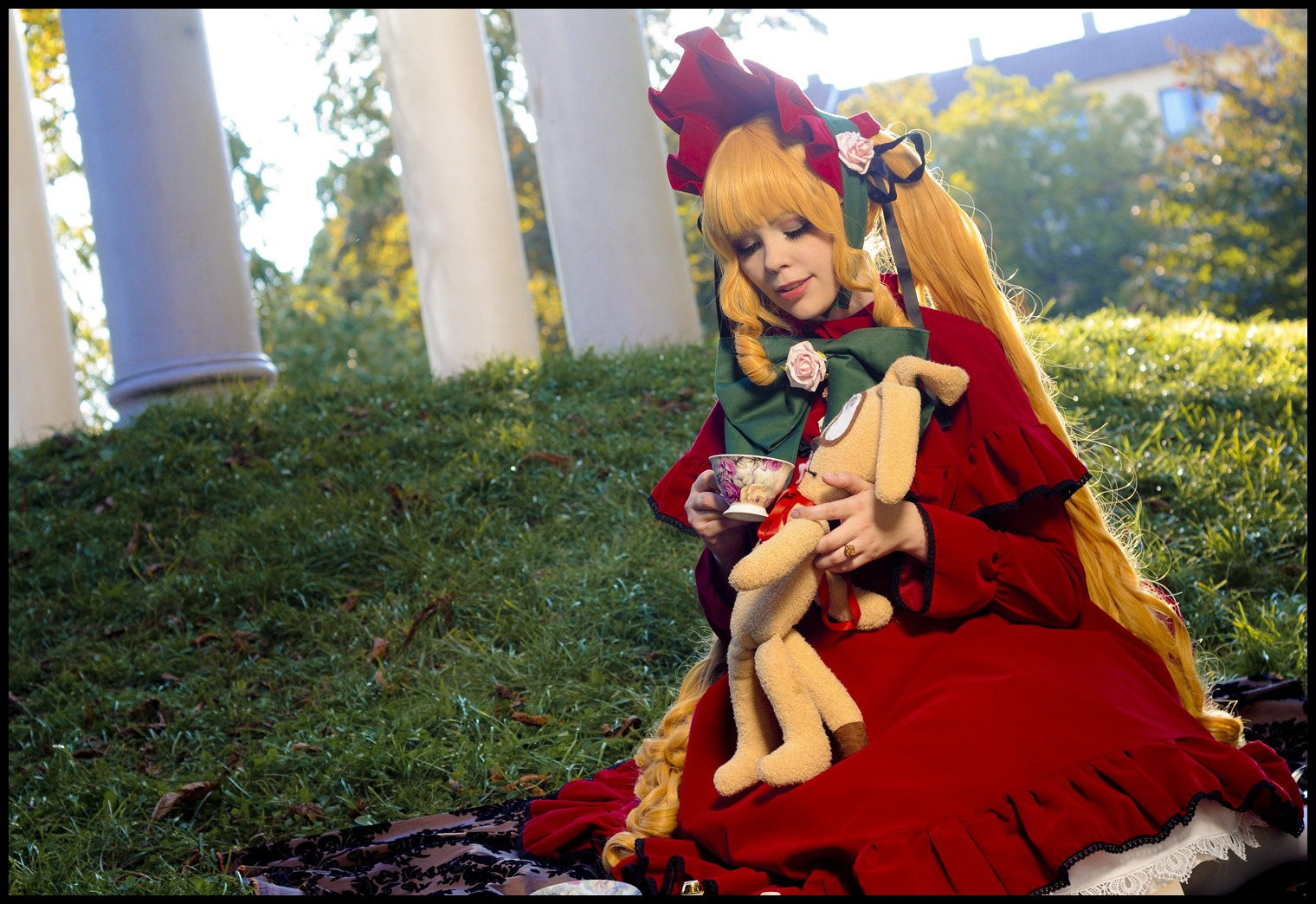 1girl black_border blonde_hair bonnet bow doll doll_joints dress drill_hair flower garden letterboxed long_hair red_dress rose shinku sitting solo very_long_hair