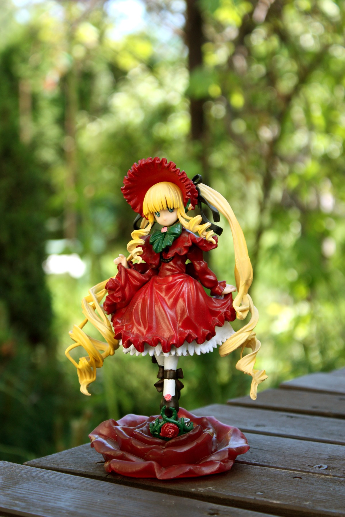 1girl blonde_hair blurry blurry_background bow depth_of_field doll dress drill_hair flower full_body long_hair long_sleeves looking_at_viewer red_dress shinku shoes solo standing very_long_hair