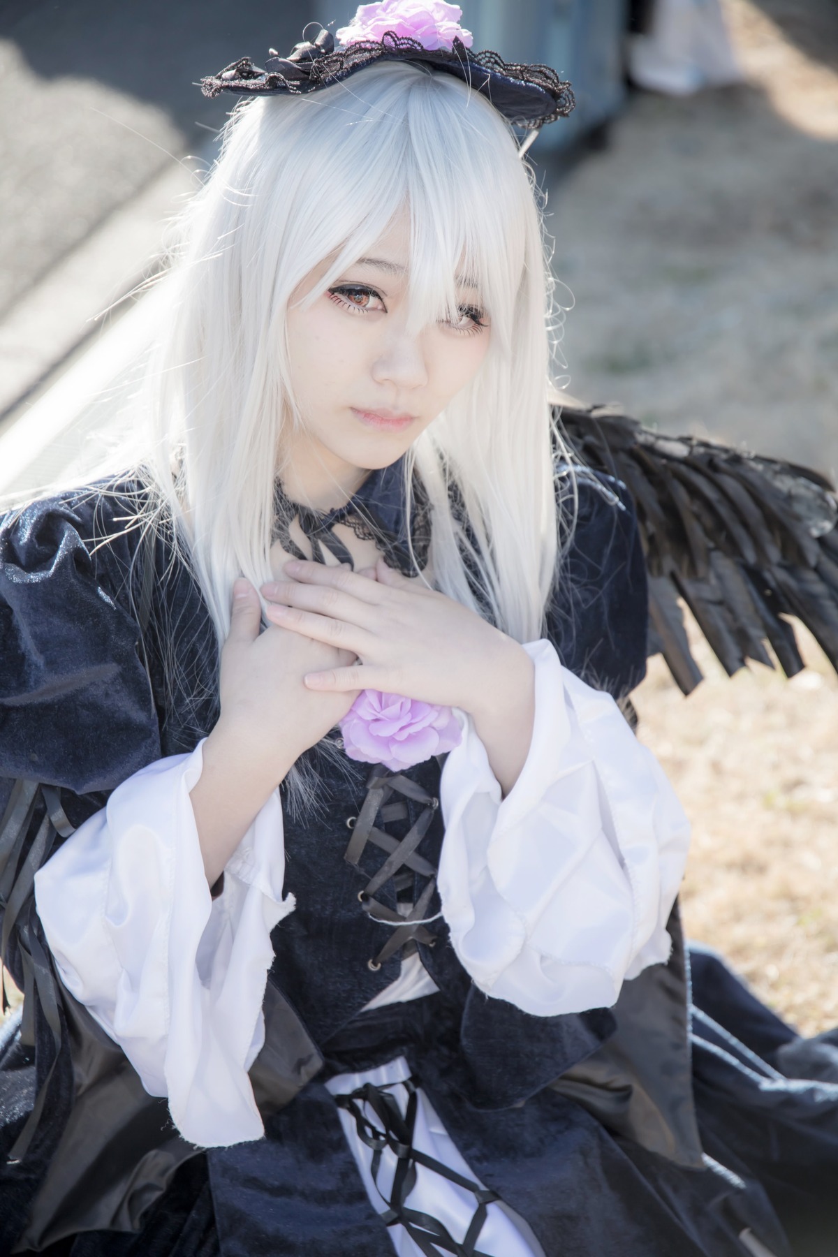 1girl bangs black_feathers blurry blurry_background blurry_foreground closed_mouth corset depth_of_field dress gothic_lolita hands_together lolita_fashion long_hair long_sleeves looking_at_viewer nail_polish own_hands_together photo ribbon solo suigintou white_hair wings